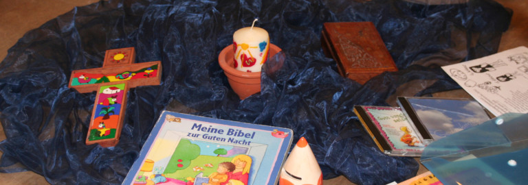 Kinderbibel, buntes Kreuz und Kerze laden zum KIndergottesdienst